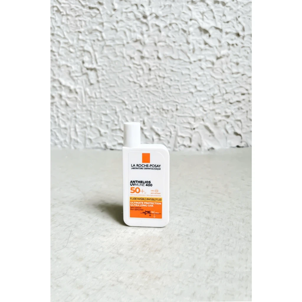 Kem chống nắng La Roche-Posay Anthelios UVMune 400 SPF50+ trong chai nhựa trắng, nhãn sản phẩm màu cam và đen, đặt trên nền sáng.