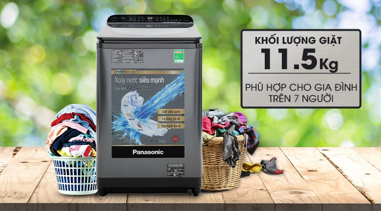 Máy giặt Panasonic NA-FS14X7LRV màu đen, có khả năng giặt 11.5kg, đặt trên bàn gỗ với giỏ quần áo hai bên