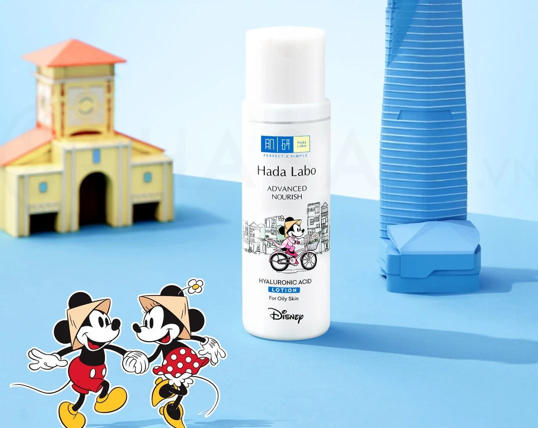 Chai tinh chất dưỡng ẩm Hada Labo Advanced Nourish Hyaluronic Acid Lotion phiên bản Disney, có hình ảnh Mickey và Minnie, đặt trên nền xanh với đồ chơi mô hình phía sau.